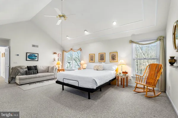 a bedroom with a bed a couch and potted plant on the dresser