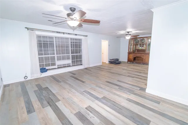 a view of an empty room with a window and a ceiling fan