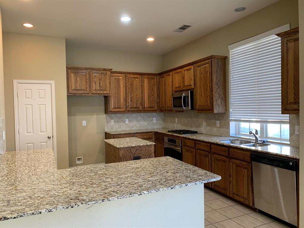 1017 Somerset Circle Forney, TX 75126 - Photo 5 of 21 a kitchen with stainless steel appliances granite countertop wooden cabinets a stove top oven a sink and dishwasher