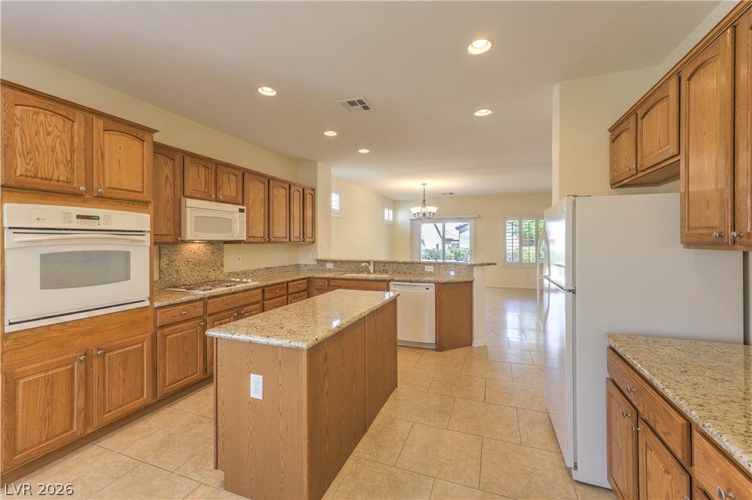 2276 Saxtons River Road Henderson, NV 89044 - Photo 12 of 49 Island Kitchen features Granite Countertops, Upgraded Cabinets w/ Pull-Out Shelves, Breakfast Bar, Nook, Pantry, Tile Flooring, Recessed Lighting, Built-In Oven w/ Convection, Gas Cooktop, Microwave, and Dishwasher