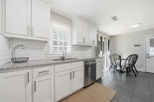 a kitchen with granite countertop white cabinets and stainless steel appliances