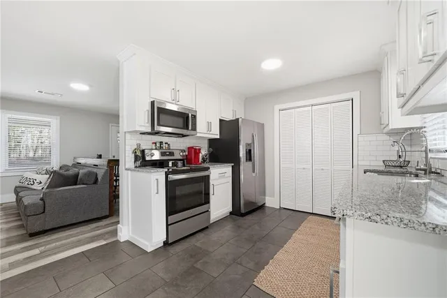a kitchen with granite countertop a refrigerator and a stove top oven
