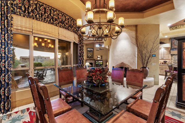 a view of a dining room with furniture a chandelier and large windows