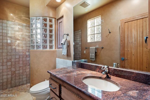 a bathroom with a granite countertop sink toilet a mirror and shower curtain