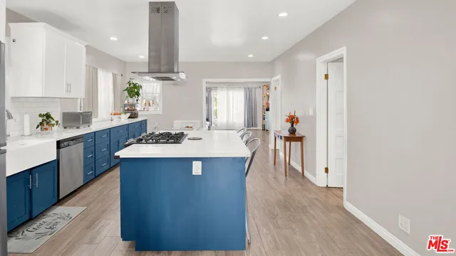a kitchen with stainless steel appliances a sink stove and wooden floor