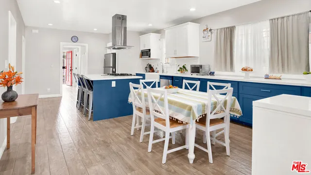 a kitchen with stainless steel appliances kitchen island granite countertop a table chairs sink and cabinets