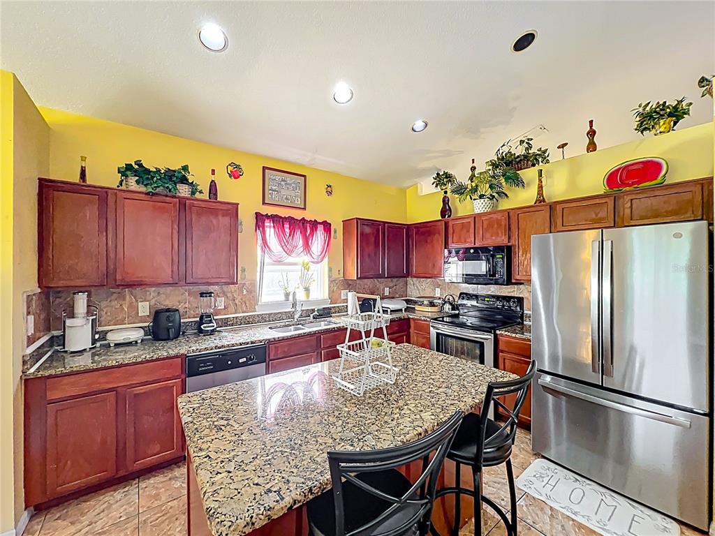 7939 Riffle Lane Orlando, FL 32818 - Photo 12 of 52 a kitchen with stainless steel appliances granite countertop a refrigerator sink stove dining table and chairs