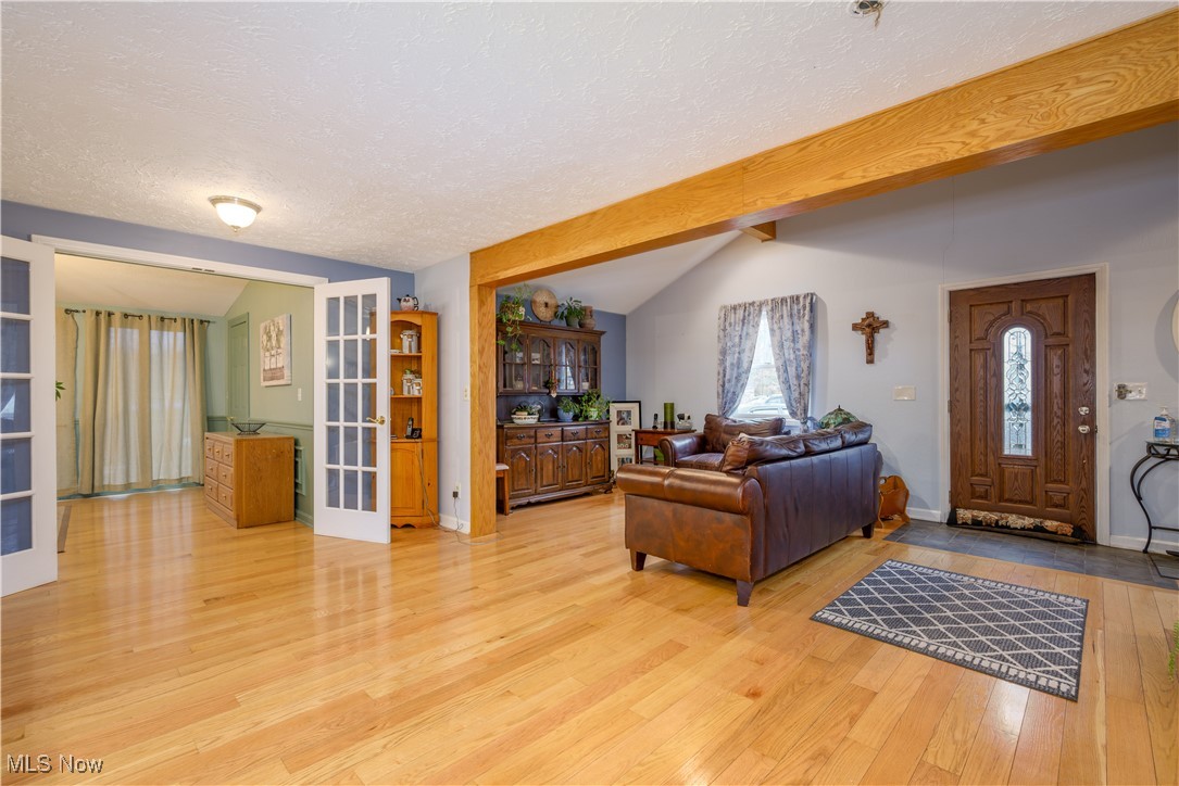 17080 Heiser Road Berlin Center, OH 44401 - Photo 24 of 35 Living room with french doors, lofted ceiling with beams, a textured ceiling, and light wood-type flooring