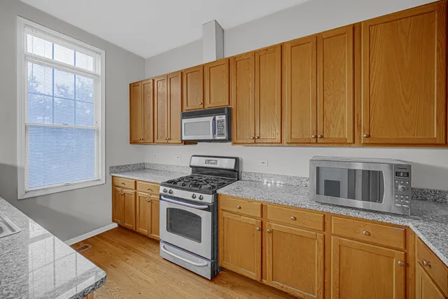 a kitchen with stainless steel appliances granite countertop a stove a sink dishwasher and microwave with wooden cabinets