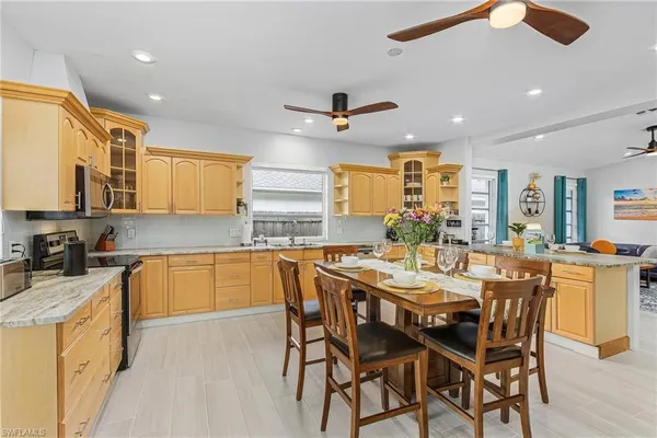 a kitchen with stainless steel appliances granite countertop wooden cabinets a stove a sink a dining table and chairs
