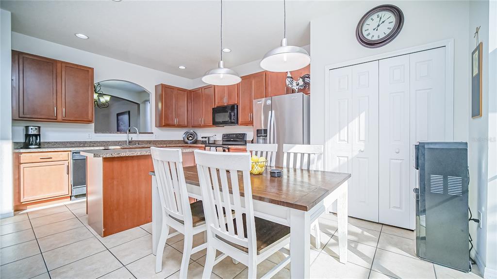 2528 Dharma Circle Kissimmee, FL 34746 - Photo 13 of 46 a kitchen with stainless steel appliances granite countertop a table chairs and a refrigerator