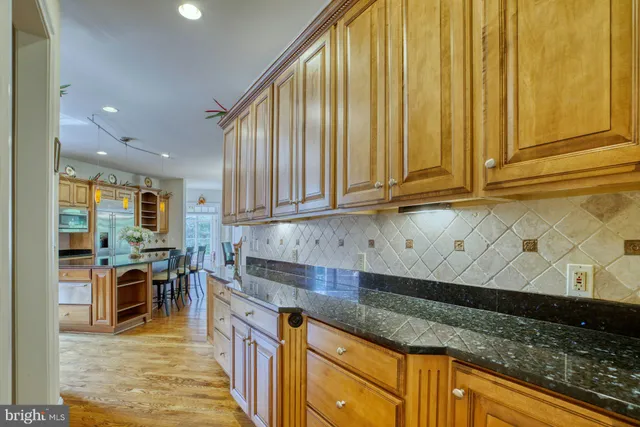 a kitchen with stainless steel appliances granite countertop a stove top oven a sink dishwasher and a dining table with wooden floor