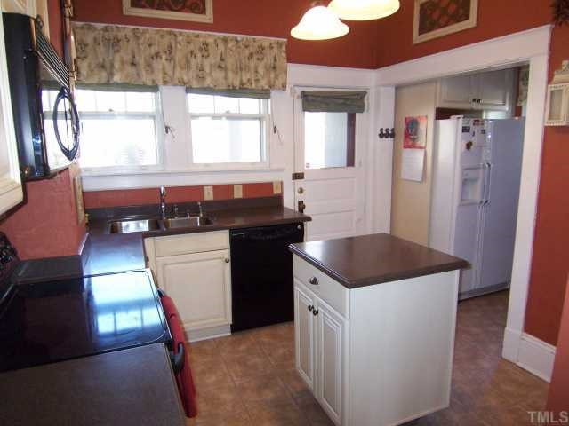 519 Gardner Street Raleigh, NC 27607 - Photo 7 of 12 Kitchen as viewed from dining room side. Kitchen has movable island, corian countertops and a double stainless steel sink. There is a coffee counter and cabinet beside the refrigerator which is in the original breakfast nook. Kitchen
