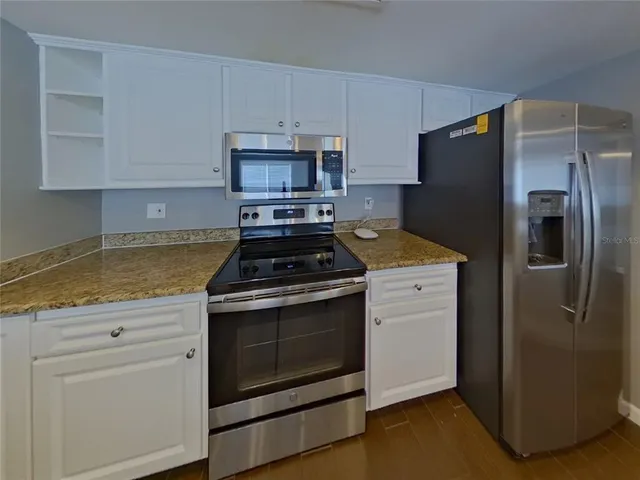 a kitchen with stainless steel appliances white cabinets a sink and a stove