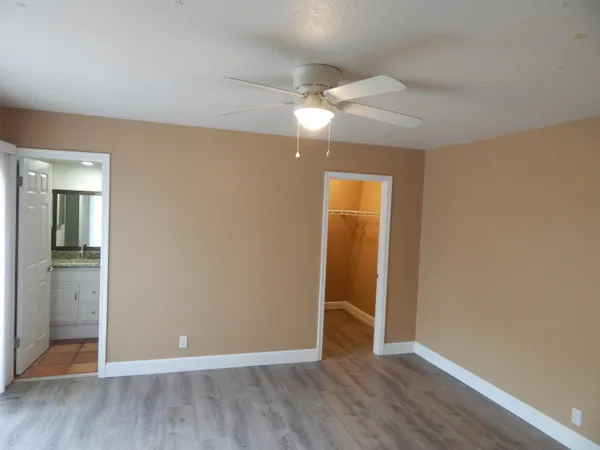 an empty room with wooden floor and a ceiling fan