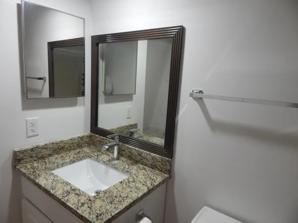 a bathroom with a granite countertop sink and a mirror
