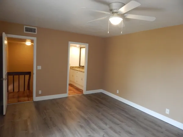 an empty room with wooden floor closet and windows