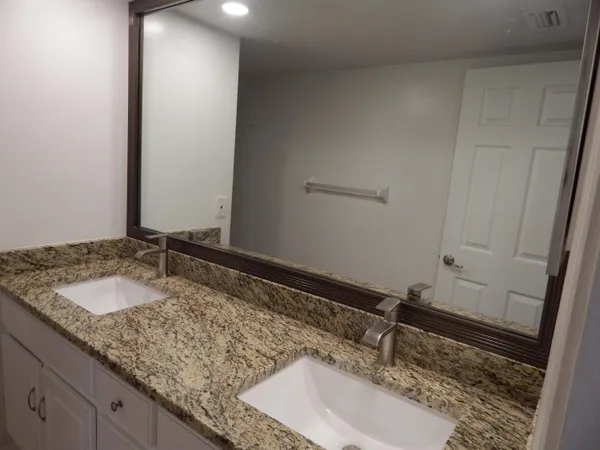 a bathroom with a granite countertop sink and a mirror