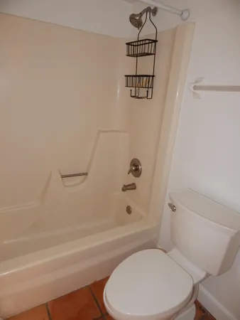 a white toilet sitting next to a bath tub and a shower