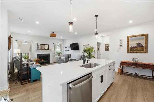 a kitchen with stainless steel appliances kitchen island granite countertop a refrigerator a stove oven and white cabinets with wooden floor