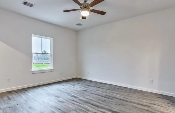 an empty room with wooden floor chandelier fan and windows