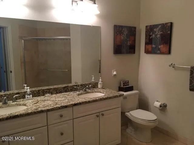 a bathroom with a granite countertop toilet sink and mirror