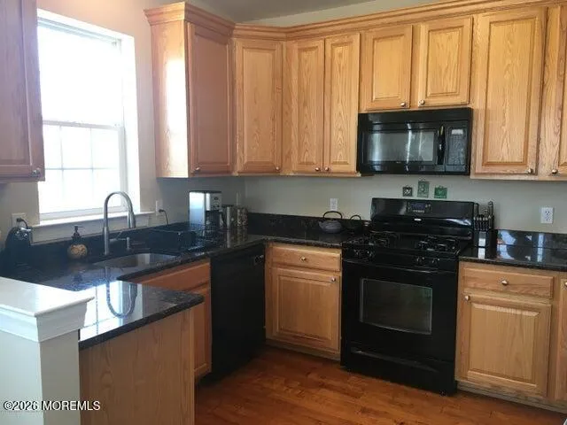a kitchen with granite countertop a stove a sink and a microwave