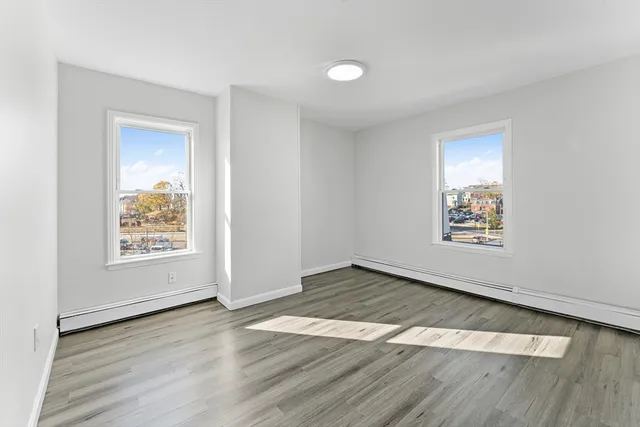an empty room with wooden floor and window