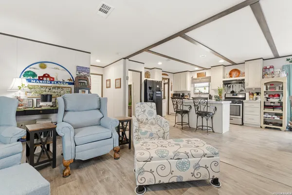 a living room with furniture kitchen view and a wooden floor