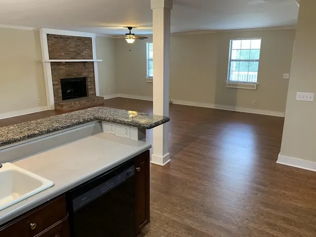 an empty room with wooden floor fireplace and windows