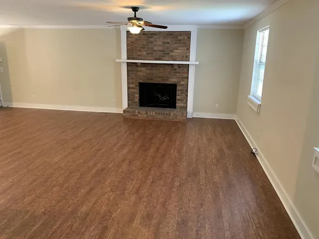an empty room with wooden floor fireplace and windows