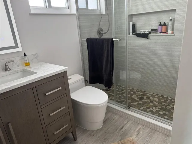 a bathroom with a granite countertop sink toilet mirror and bathtub