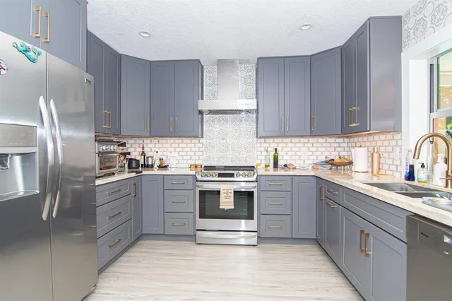 a kitchen with stainless steel appliances granite countertop a stove top oven a sink and dishwasher a refrigerator with wooden cabinets