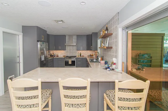 a kitchen with kitchen island a stove a sink a refrigerator and a dining table