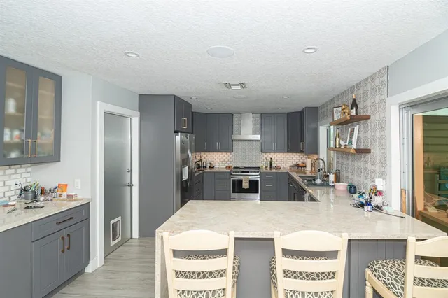 a kitchen with stainless steel appliances kitchen island granite countertop a sink refrigerator and cabinets