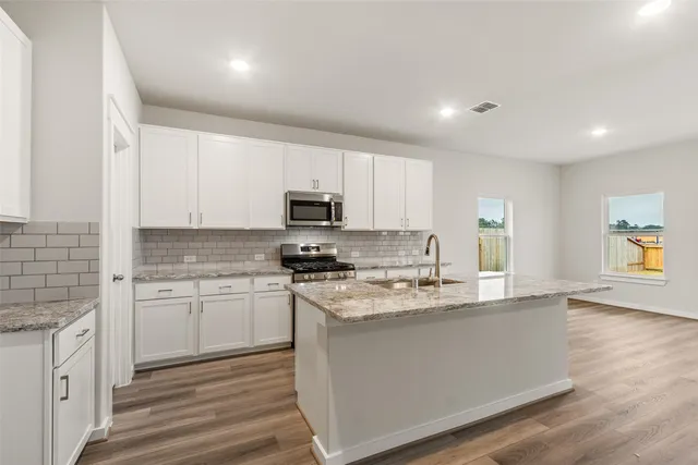 a kitchen with stainless steel appliances granite countertop a stove a sink and a microwave