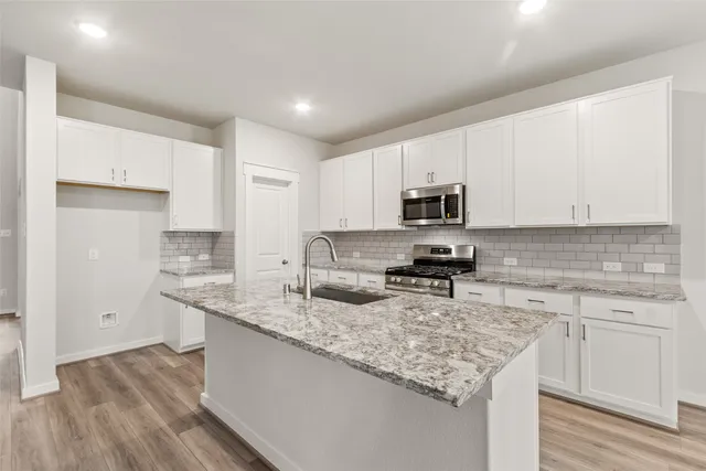 a kitchen with granite countertop cabinets stainless steel appliances a sink and wooden floor