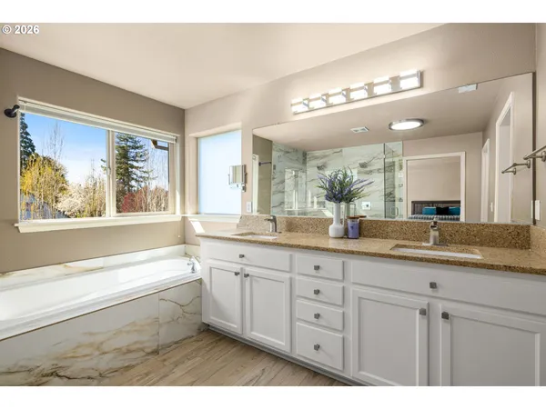 a bathroom with a sink a large mirror and a bathtub next to a window