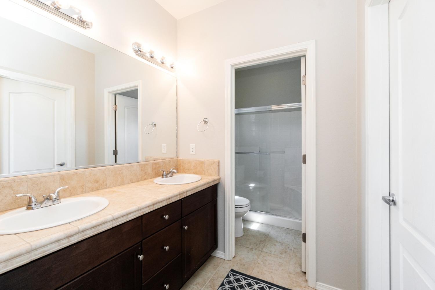 4103 Harlan Ranch Boulevard Clovis, CA 93619 - Photo 22 of 31 a bathroom with a granite countertop sink a toilet and a shower