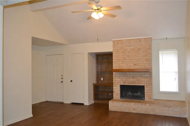 a view of a livingroom with a fireplace a ceiling fan and windows