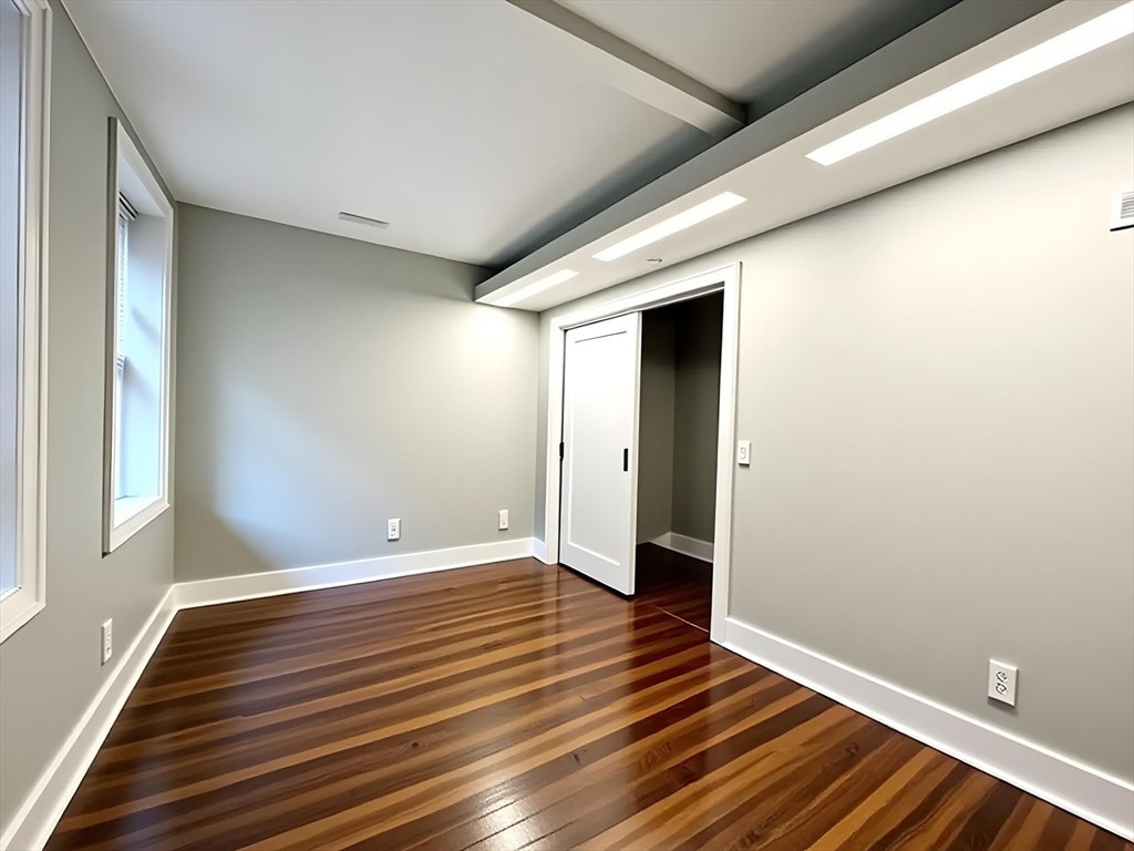 9 Anderson Street, Unit 1R Boston, MA 02114 - Photo 9 of 13 a view of an empty room with wooden floor and a window