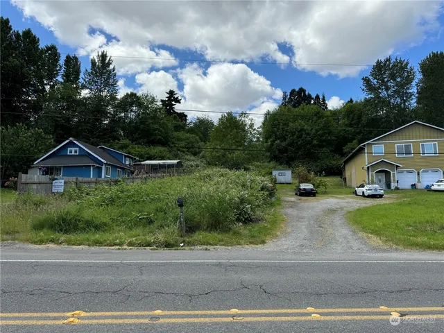 a view of a big house with a big yard plants and large trees