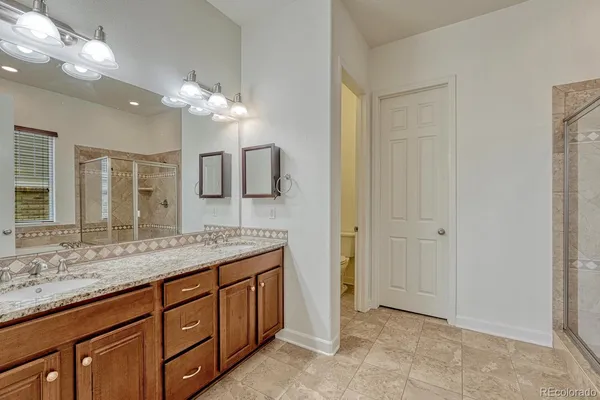 a bathroom with a granite countertop sink a mirror and a shower