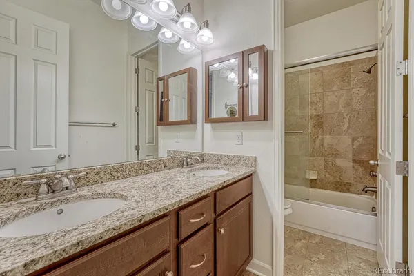 a bathroom with a granite countertop sink a mirror and a bathtub