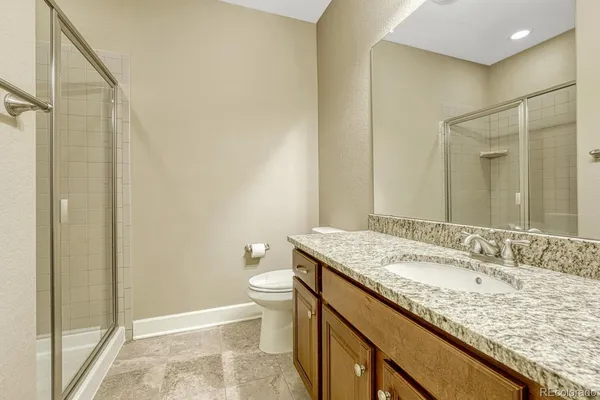 a bathroom with a granite countertop sink toilet and shower