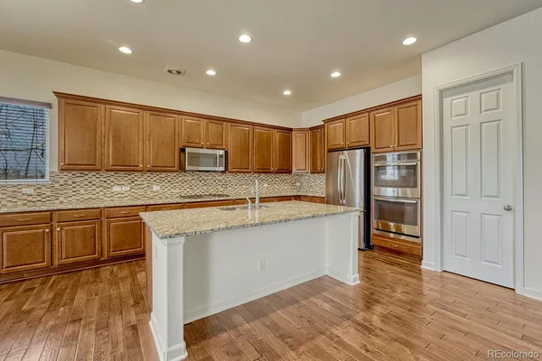 a kitchen with stainless steel appliances granite countertop a refrigerator and wooden cabinets