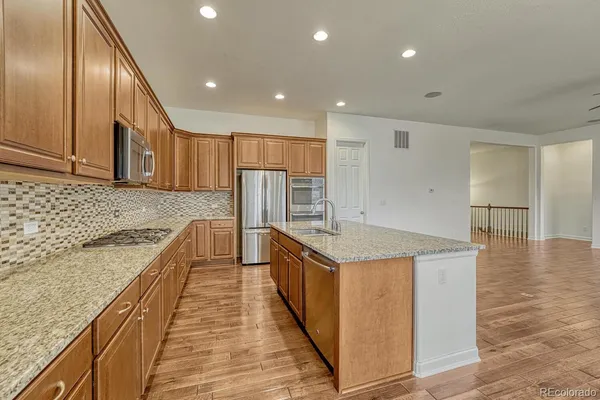 a kitchen with stainless steel appliances granite countertop a sink and a refrigerator