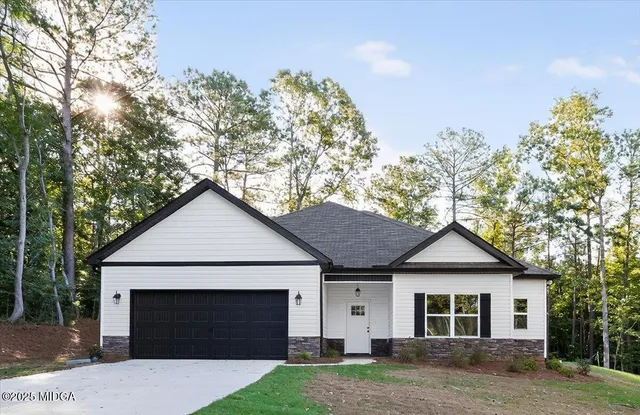 a front view of a house with a garden and trees