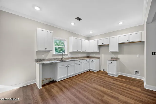 a kitchen with granite countertop white cabinets stainless steel appliances a sink and a window