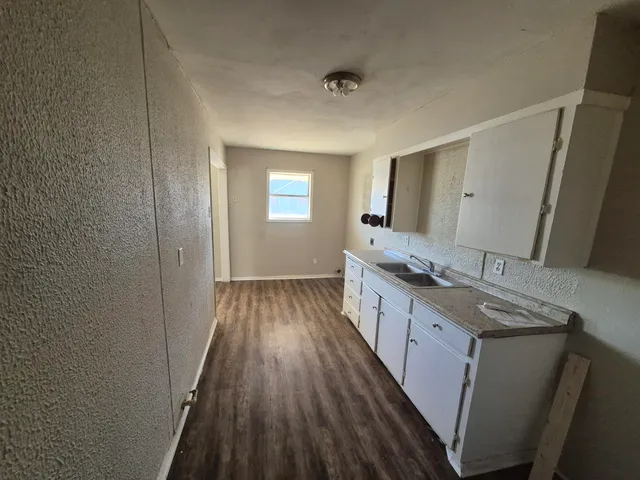 a kitchen with granite countertop wooden floors and white cabinets